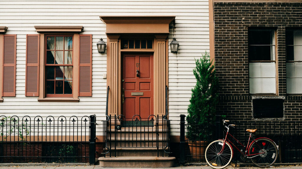 red bicycle parked beside black metal gate in front house