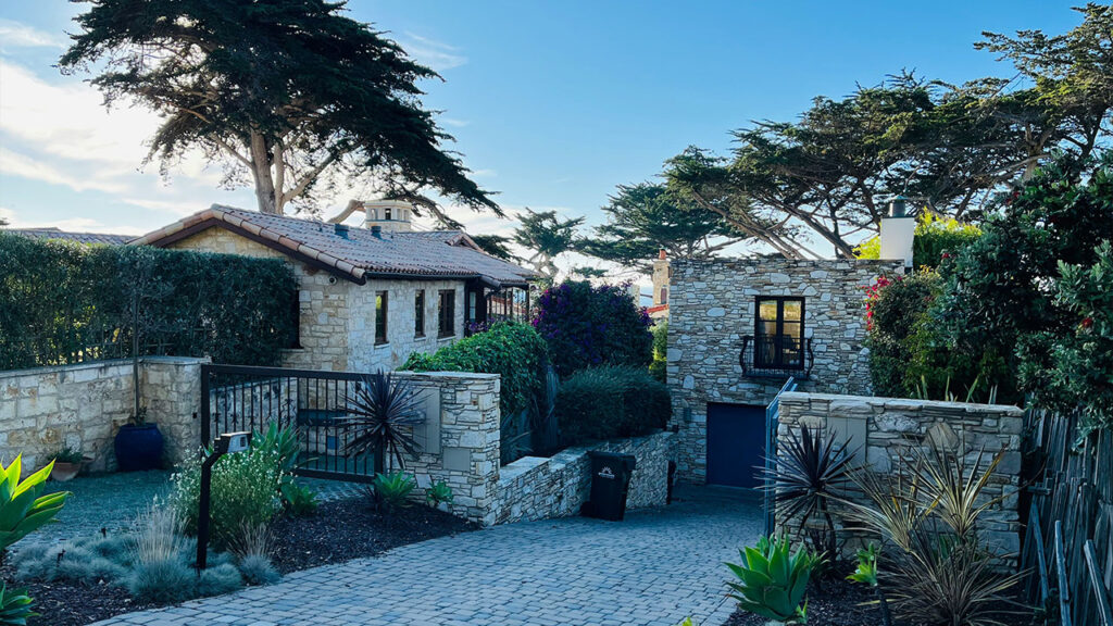 A stone house with a driveway and trees in the background