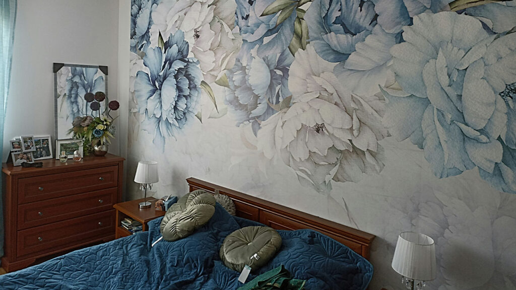 a bed room with a neatly made bed and a painting on the wall