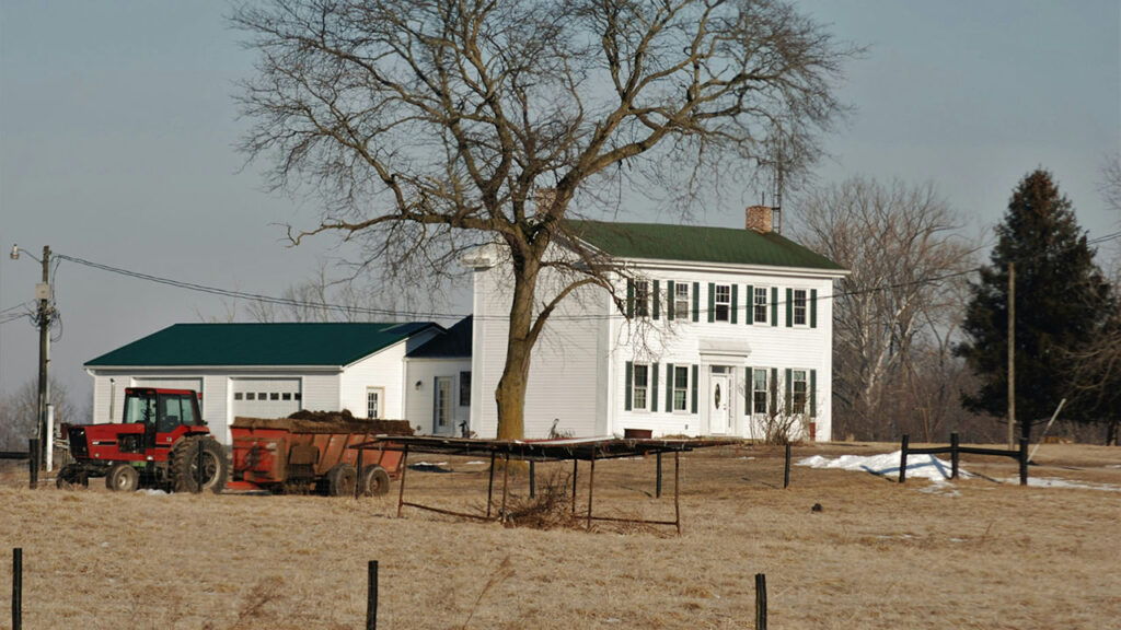 a farm house with a tractor parked in front of it