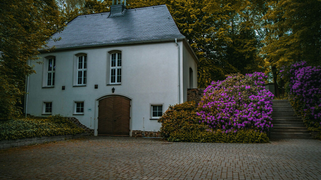 a white house with purple flowers in front of it