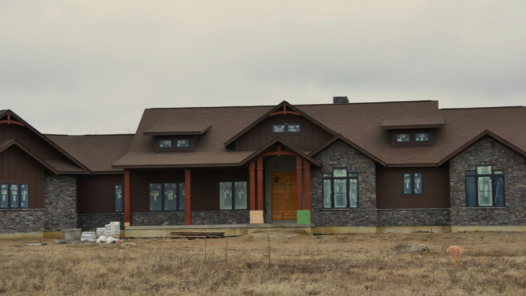 a large brown house sitting on top of a dry grass field