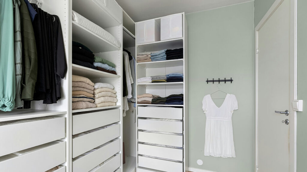 A walk in closet filled with lots of white drawers