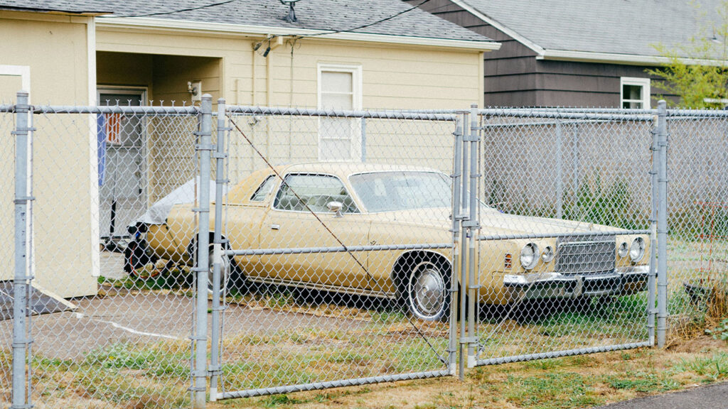 white and brown sedan parked beside white metal fence during daytime