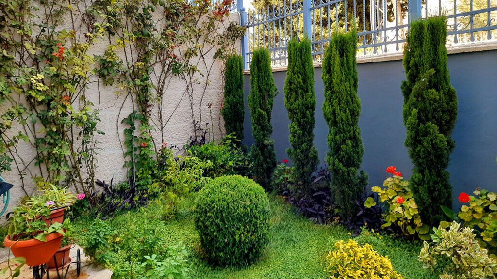 a garden area with a fence, potted plants, and a lawn chair