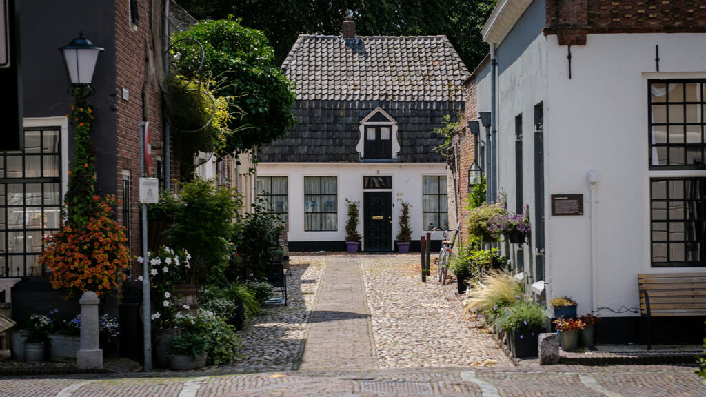 a cobblestone street with a white house in the background