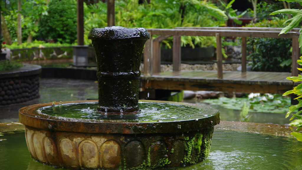 a water fountain with a wooden bridge in the background