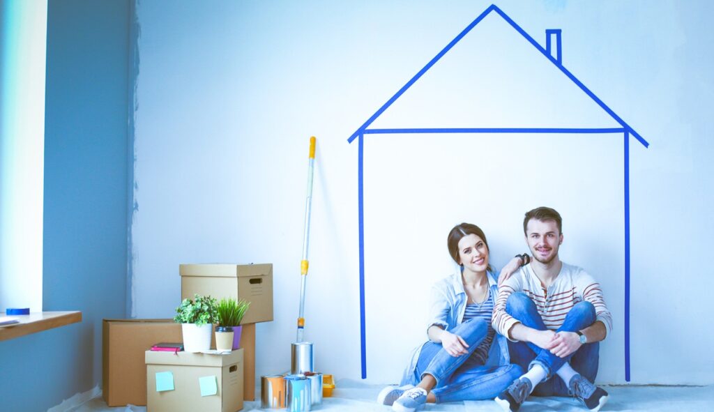 Couple sitting in front of painted home on wall