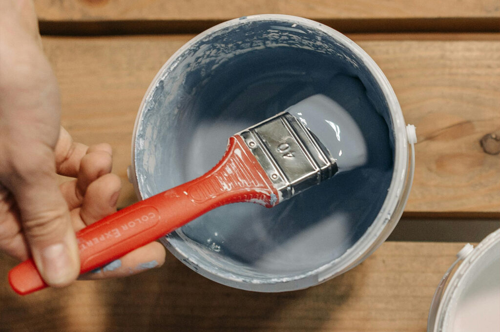 dipping paintbrush in paint can