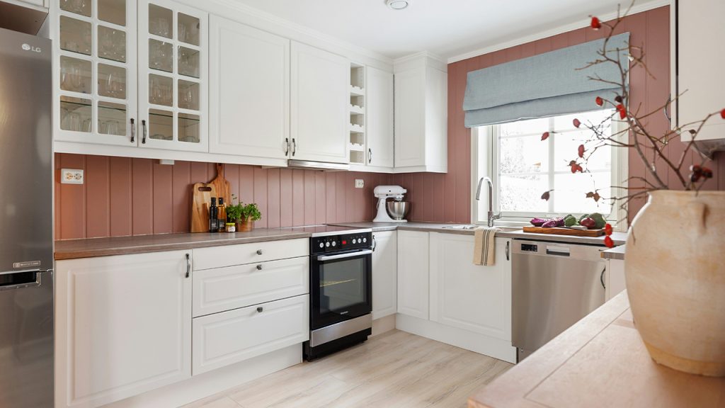 A kitchen with white cabinets and wood floors