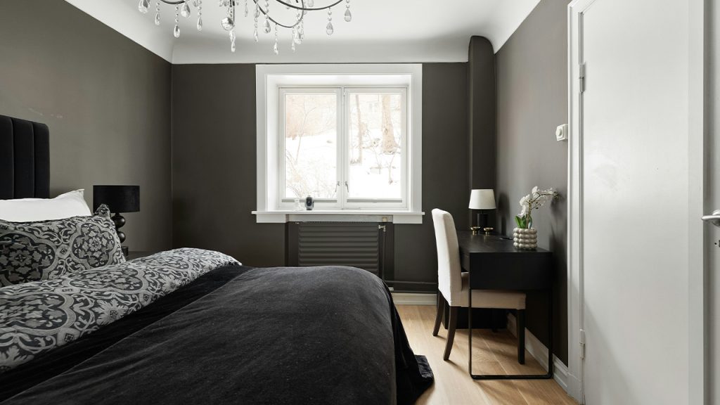 A bedroom with a bed, desk and a chandelier