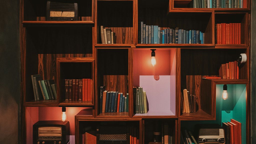 a bookshelf filled with lots of books next to a lamp