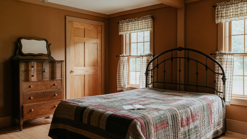 A bed sitting in a bedroom next to two windows