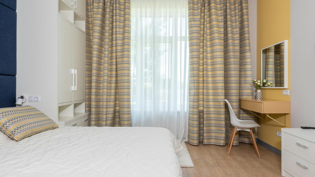Modern furnished bedroom with large bed and striped curtains
