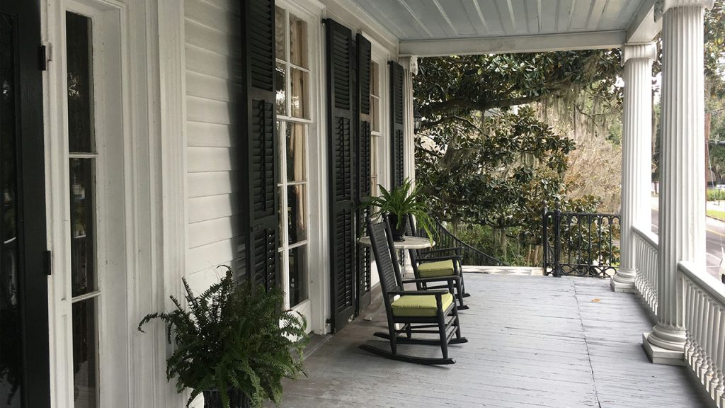 a porch with rocking chairs and a potted plant