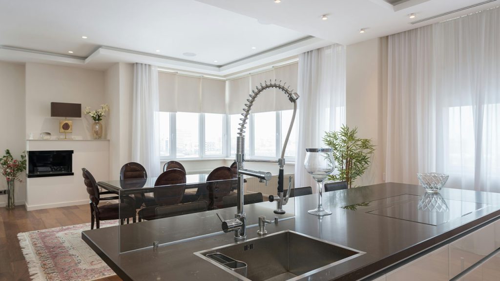 Kitchen island with sink in modern apartment with dining zone