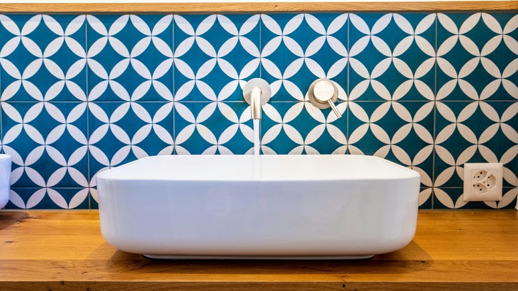 white ceramic bathtub with blue and white wall tiles