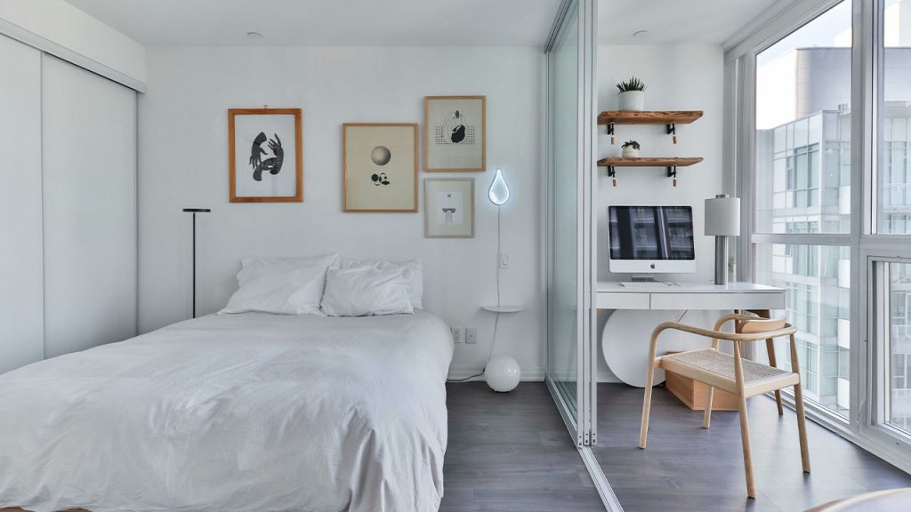 a bedroom with a bed, desk, and a window
