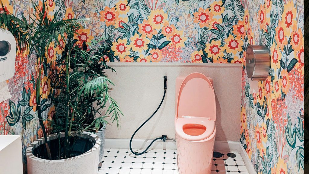 A bathroom with a toilet and a flowered wallpaper