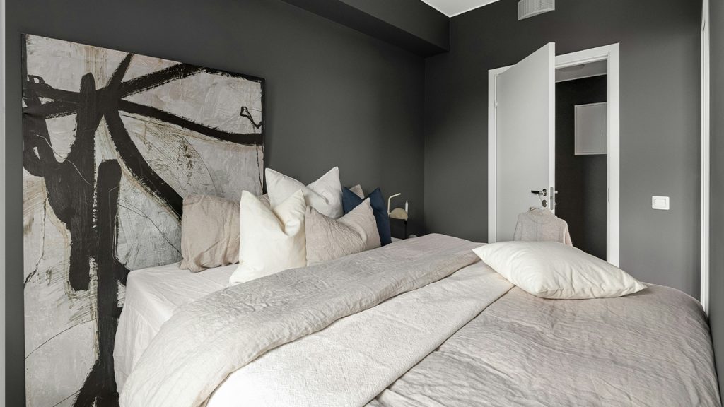 A bedroom with a large bed and a painting on the wall