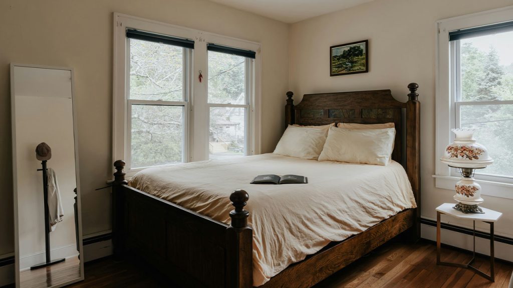 A bed sitting in a bedroom next to two windows