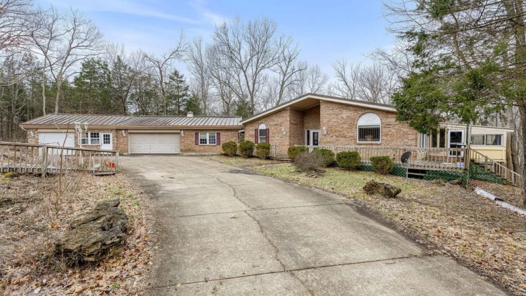 Brick ranch-style home with a three-car garage and a spacious driveway at sunset.