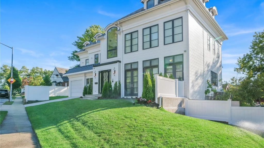A modern white Colonial-style home with black-framed windows and a manicured lawn.