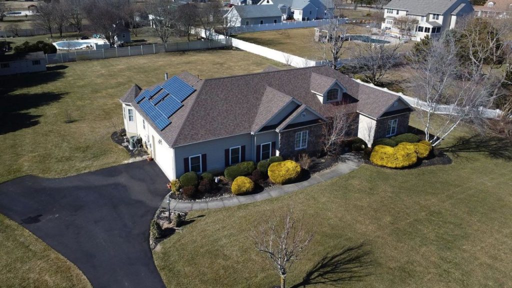 A large suburban home with solar panels, a wide driveway, and a spacious yard.