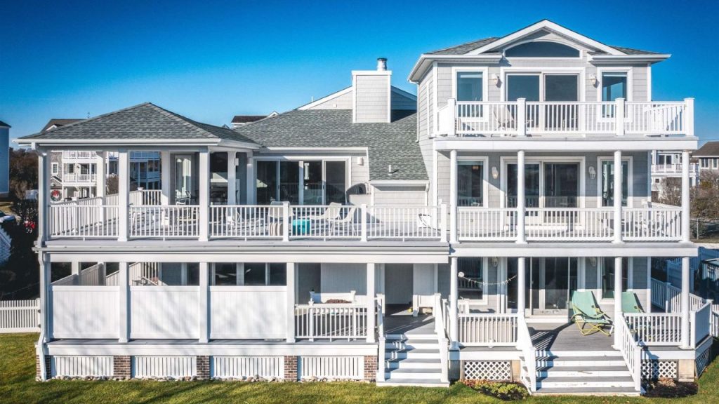 A beautiful multi-story coastal home with large balconies, white trim, and an inviting outdoor living space.