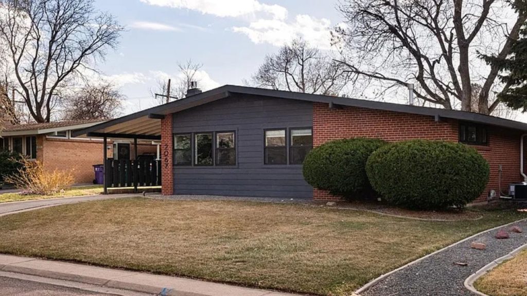 A mid-century modern home in Denver, CO, featuring a brick and dark-paneled exterior, large windows, and a neatly landscaped front yard.