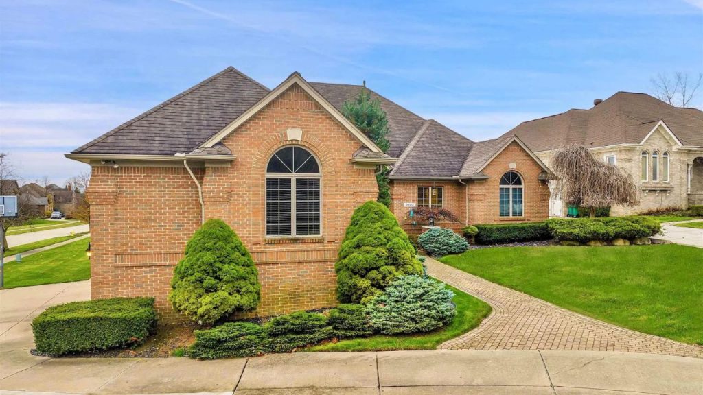 Elegant brick home with arched windows and landscaped front yard in Washington, MI