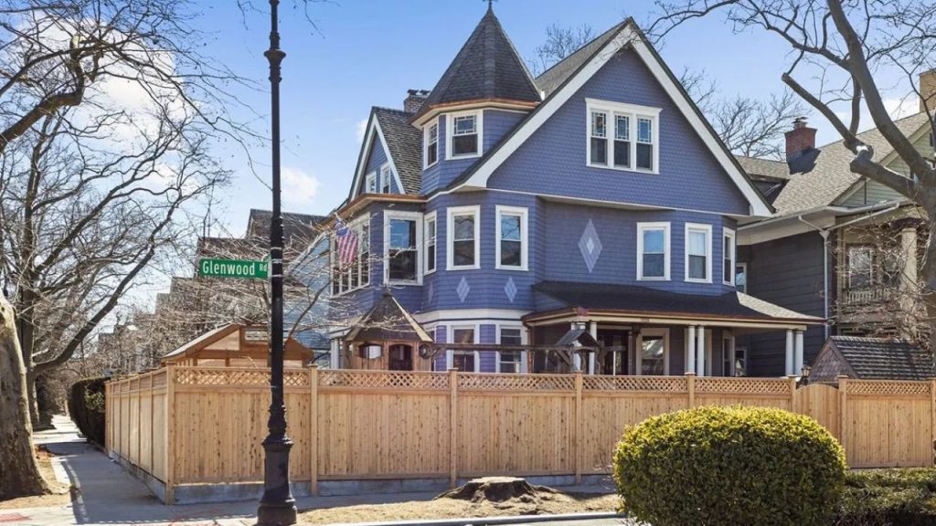 Blue multi-family home in Brooklyn with a turret, bay windows, and a wraparound porch.