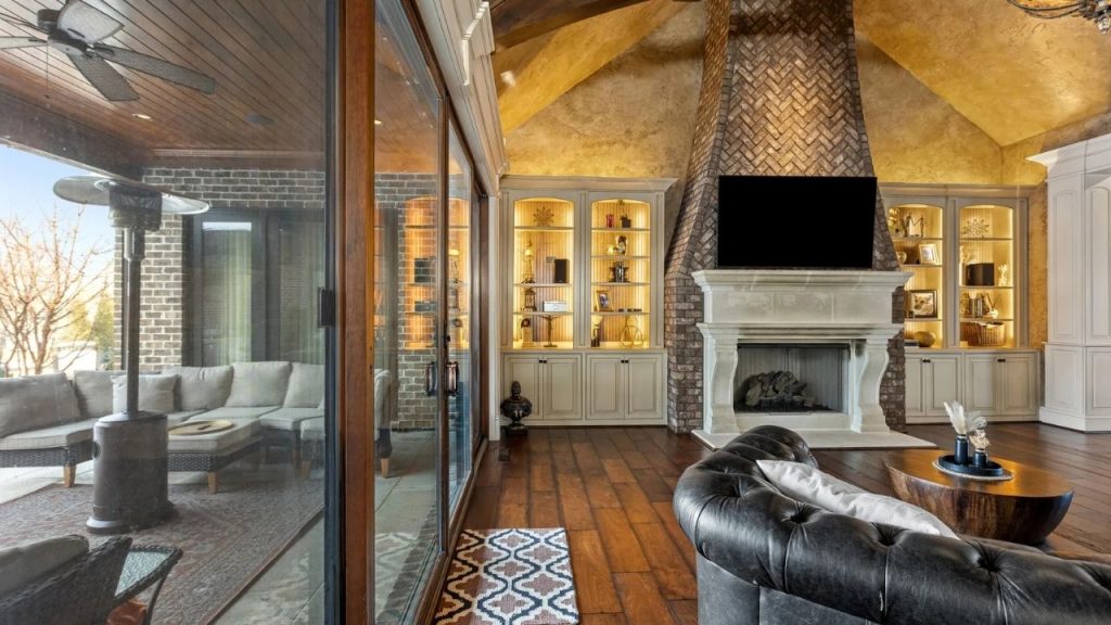 Living room with brick fireplace, built-in shelves, and glass doors to patio.