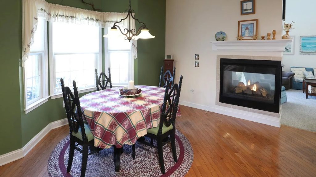 Cozy dining nook with a bay window, plaid tablecloth, and a fireplace.