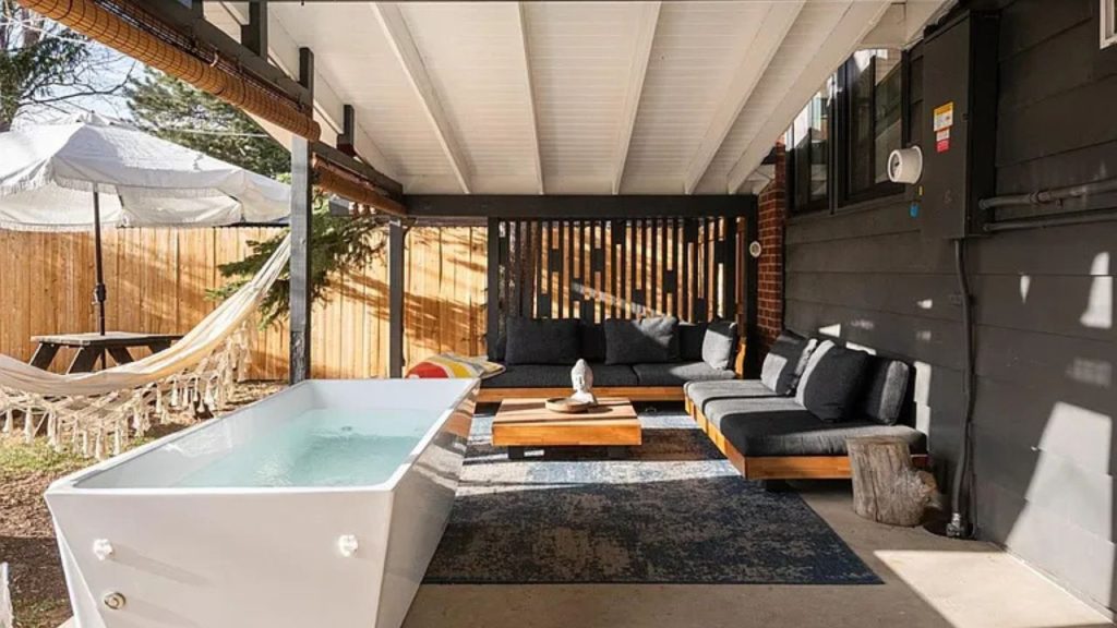 Cozy outdoor lounge with a soaking tub, hammock, and modern black seating.