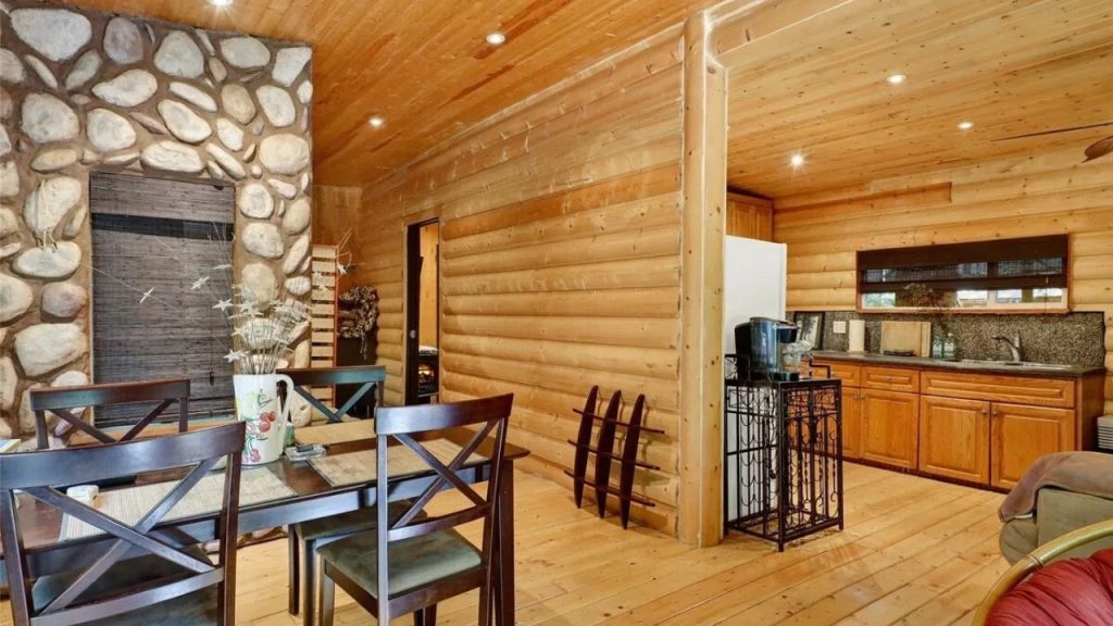 Rustic dining area with wooden table, stone accent wall, and warm lighting.