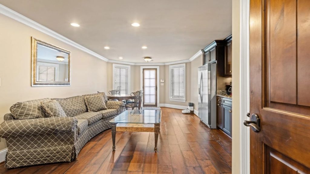 Living room with sofa, glass coffee table, and kitchenette.
