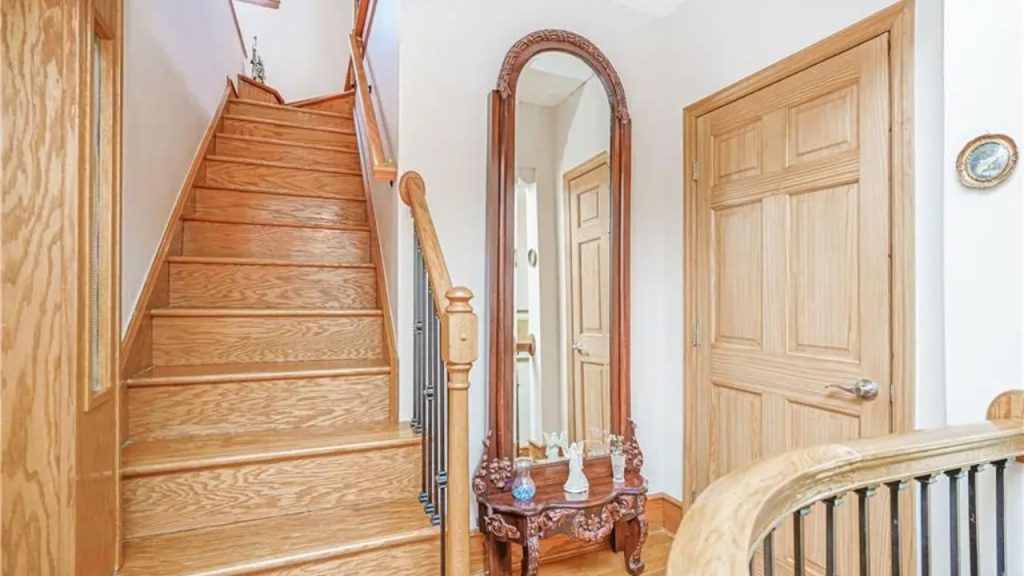 Wooden staircase with an arched mirror and decorative table.