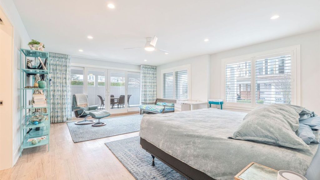 A spacious bedroom with soft blue tones, a reading nook, and a private patio.