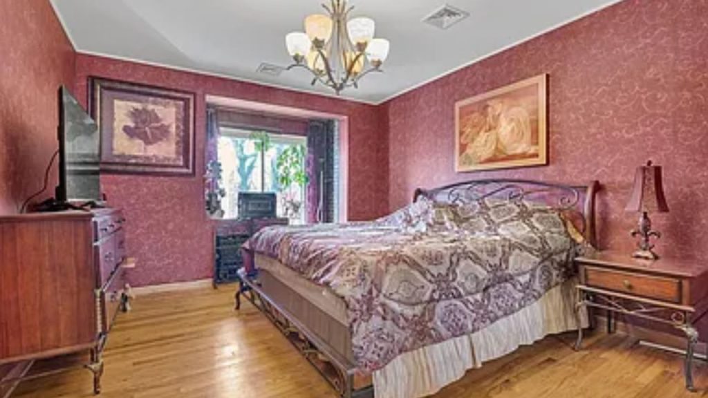 Classic bedroom with red wallpaper, vintage furniture, and warm lighting.