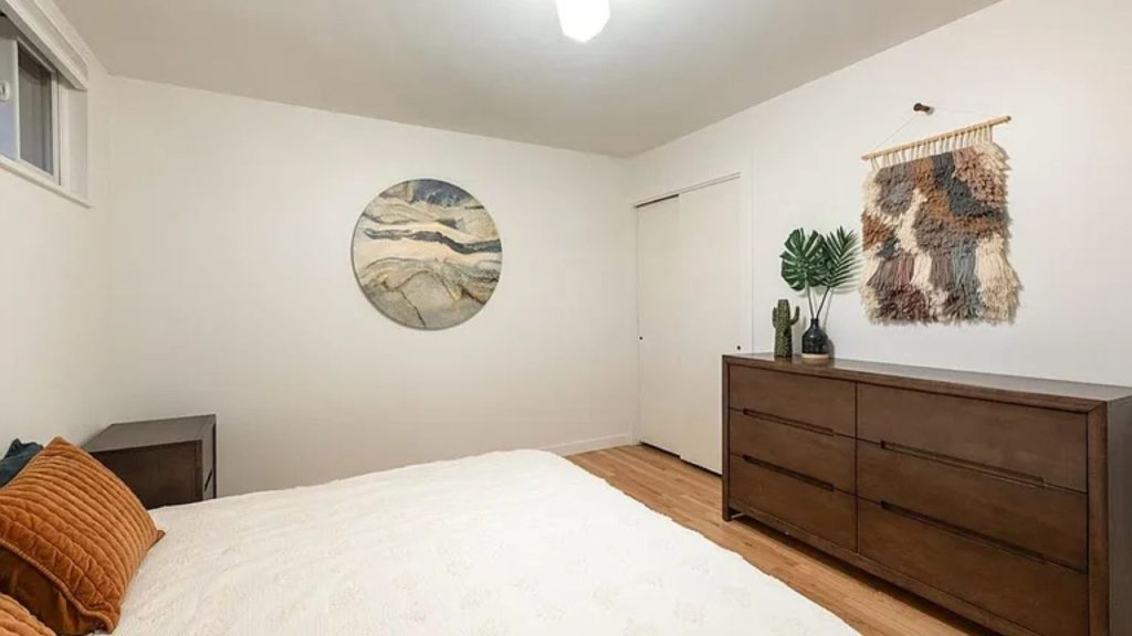 Minimalist bedroom with wooden furniture, abstract wall art, and woven textile décor.