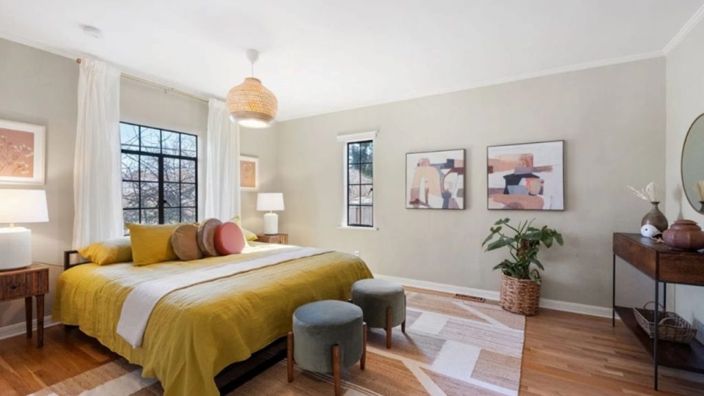 Warm and inviting bedroom with earthy tones, featuring a mustard bedspread, abstract wall art, and cozy decor.