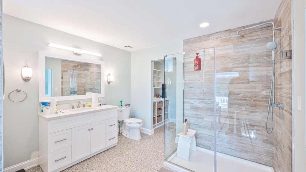 A spacious bathroom with a glass-enclosed shower, double vanity, and natural wood accents.