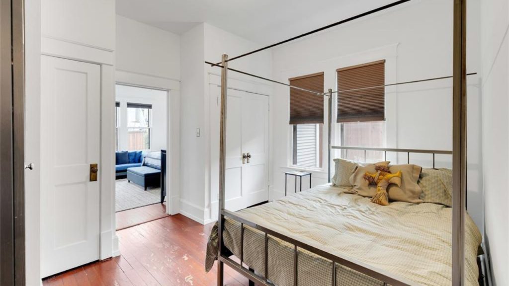 Bright bedroom with a four-poster bed, hardwood floors, and adjoining sitting area.