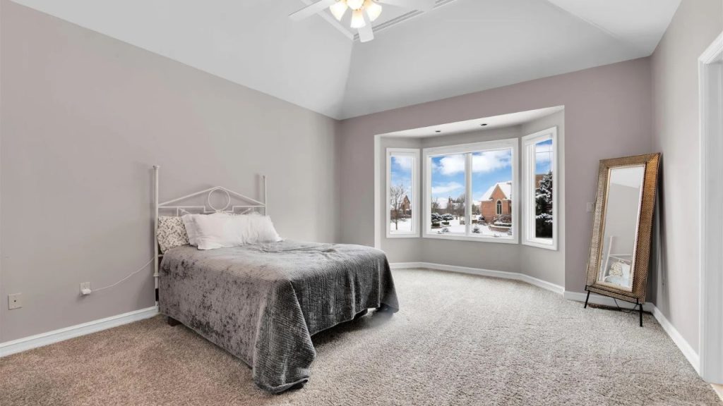 Spacious bedroom with a bay window, vaulted ceiling, and cozy decor.