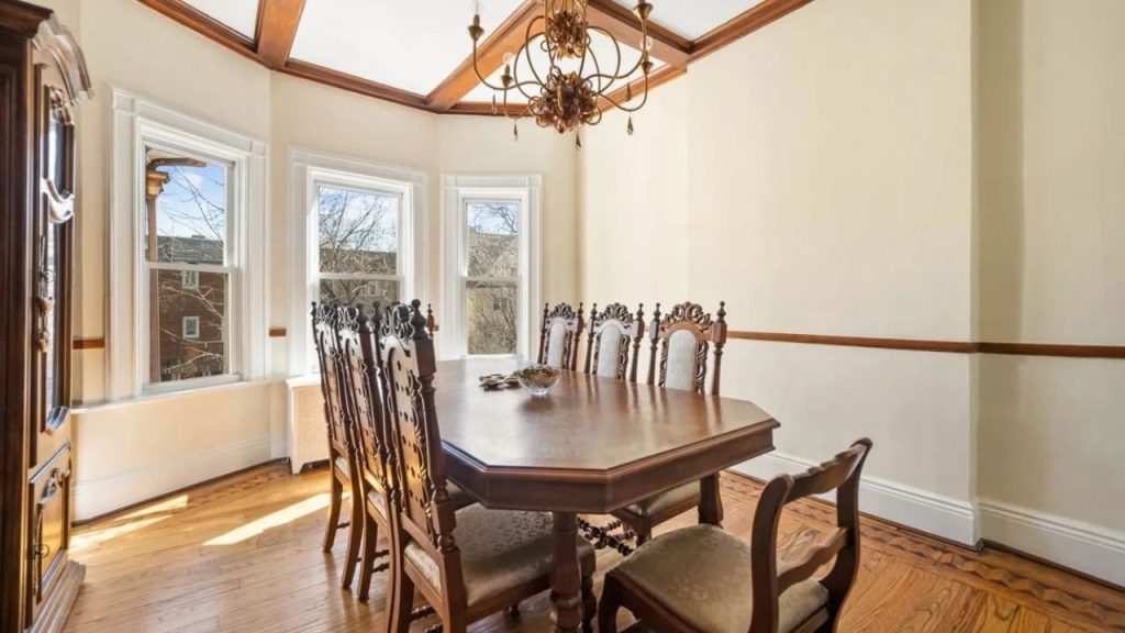 Classic dining room with antique furniture, bay windows, and a chandelier.