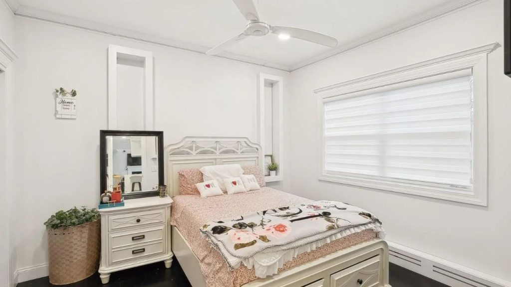 Bright and cozy bedroom with floral bedding, elegant furniture, and a ceiling fan.
