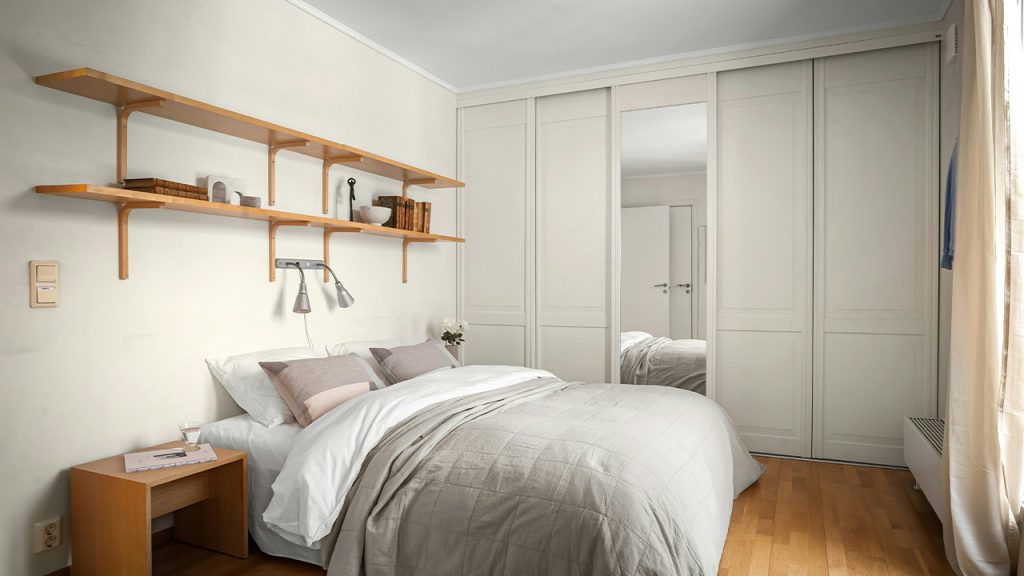 A bedroom with a bed and shelves on the wall