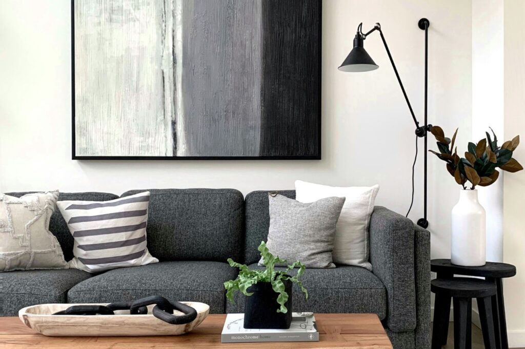 A grey sofa with black abstract art above it.