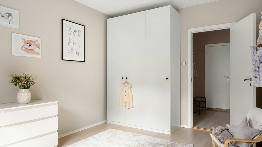A bedroom with a white dresser and a white chair